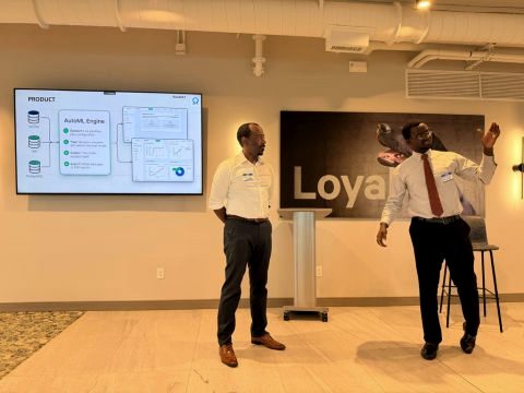Sankung Fatty stands beside a screen showing a Rassket product slide labelled ‘AutoML Engine’ while a colleague speaks and gestures.